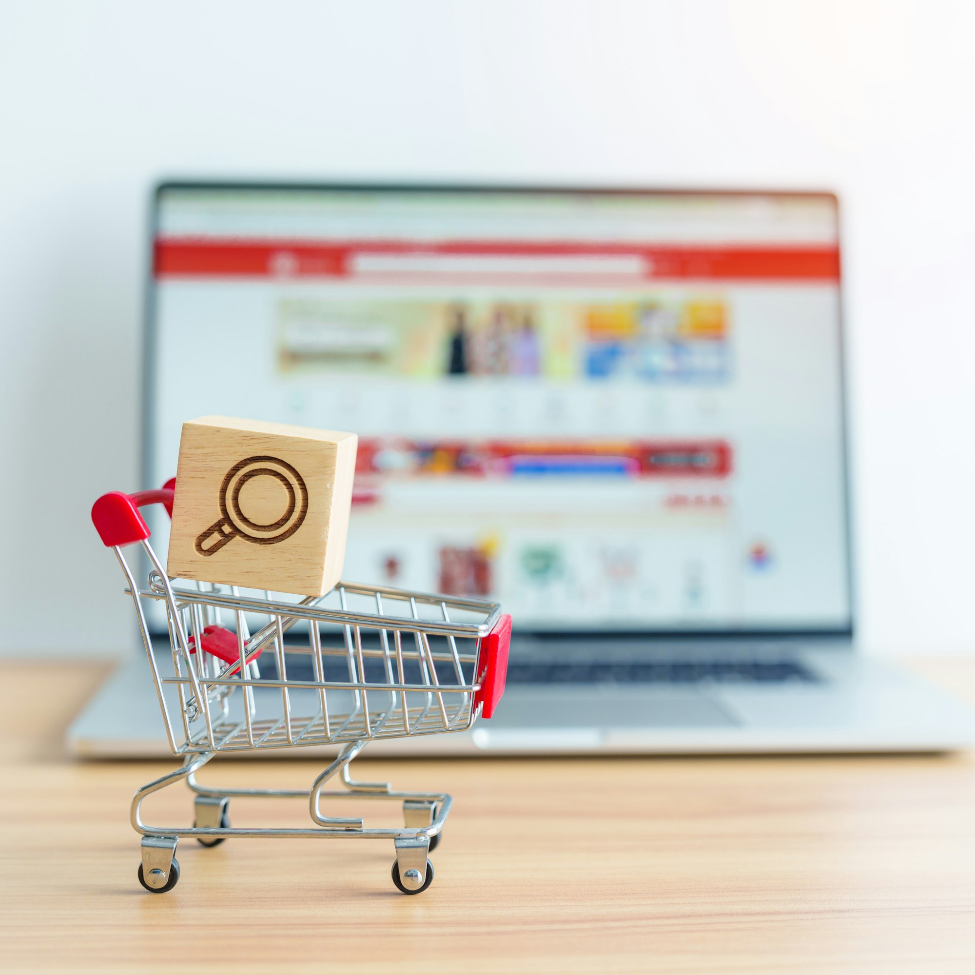 Shopping cart with Magnifying icon block and laptop computer